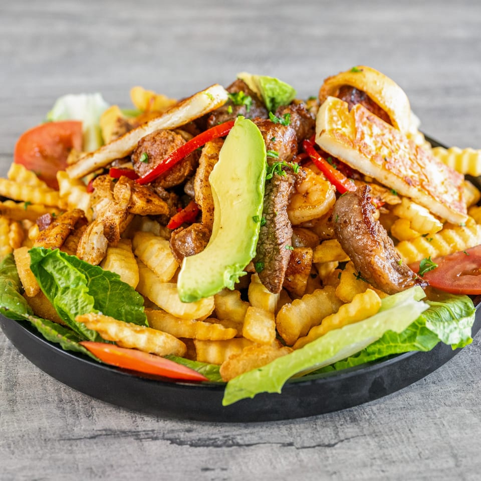 Calle El Hambre's Venezuelan dish with fries, grilled meats, shrimp, avocado, tomatoes, and lettuce.