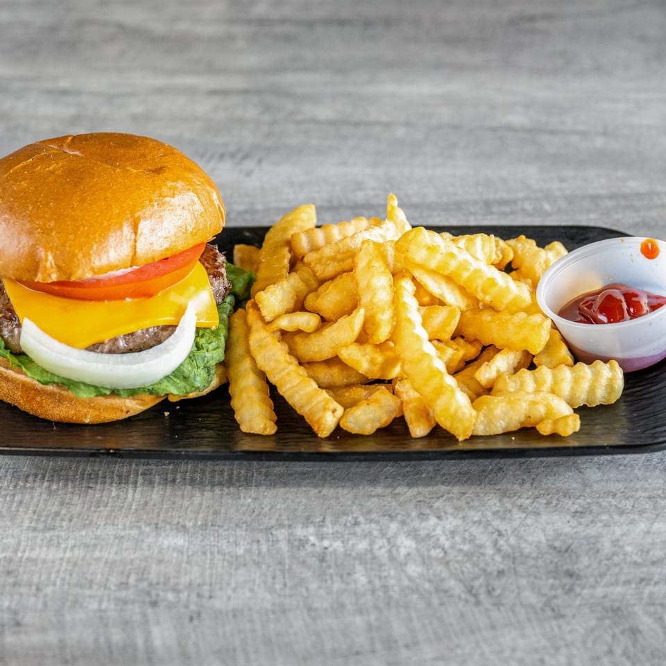 A Calle El Hambre burger with cheese, lettuce, tomato, and onion, served with crinkle-cut fries and ketchup.